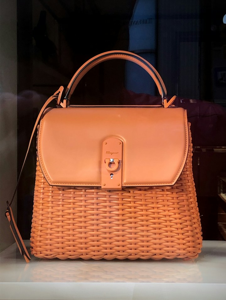 An orange woven handbag with leather handles